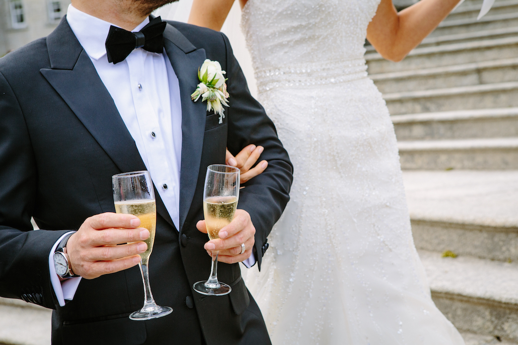 a groom wearing a black tuxedo at a wedding